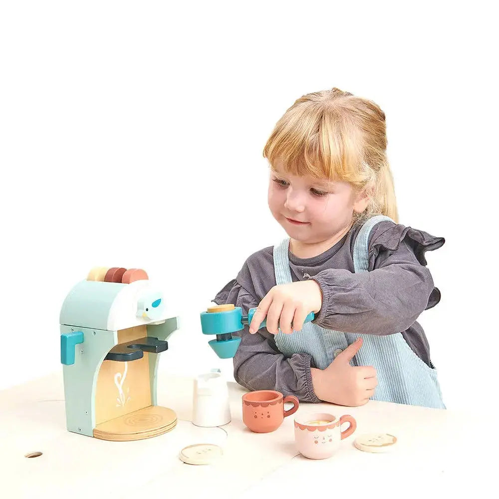 Kind bedient die Kaffeemaschine aus Holz mit Tassen und Kaffeezubehör.