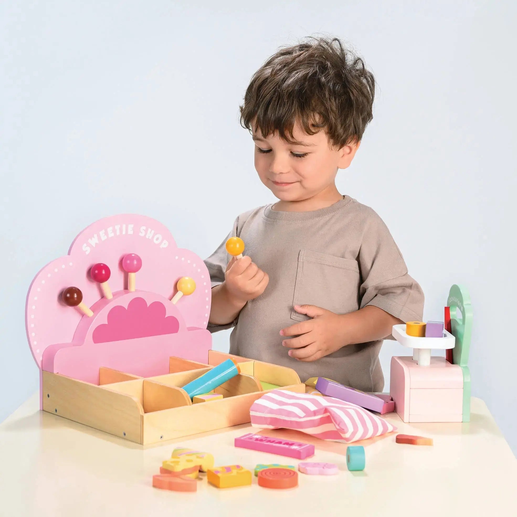 Kinder spielen mit den Süssigkeiten, der Waage und dem Verkaufszubehör des Süsswarenladens.