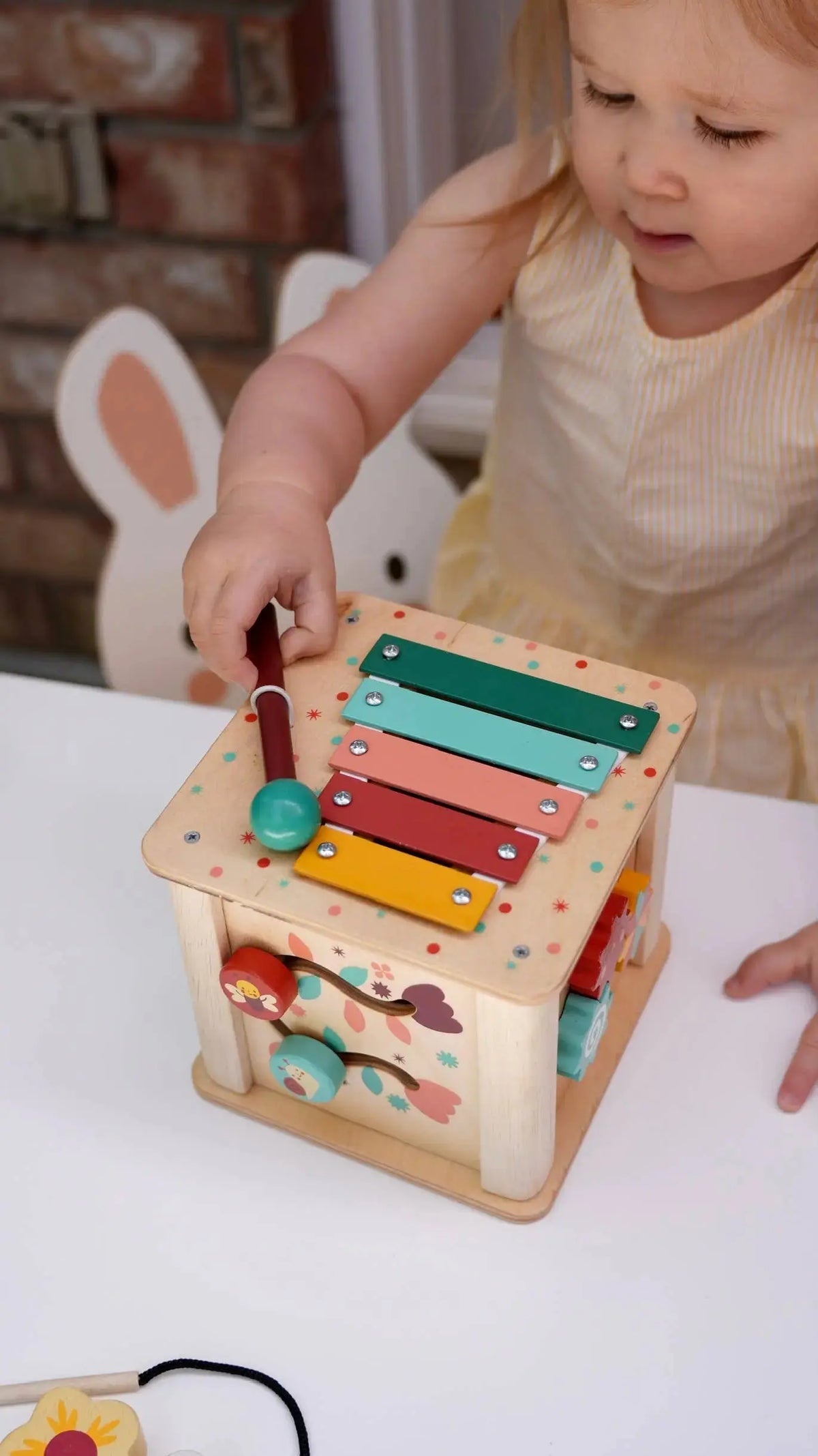 Kind spielt am Xylophon des Aktivitätswürfels aus Holz