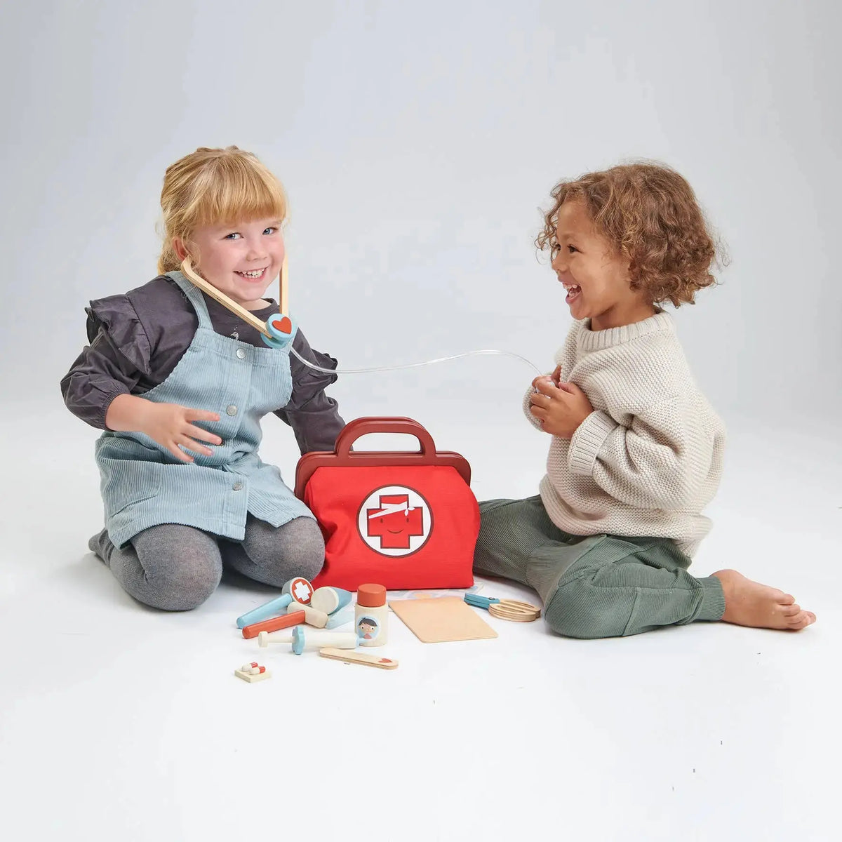 Kinder beim fantasievollen Arzt-Rollenspiel mit geöffnetem Arztkoffer und Zubehör.