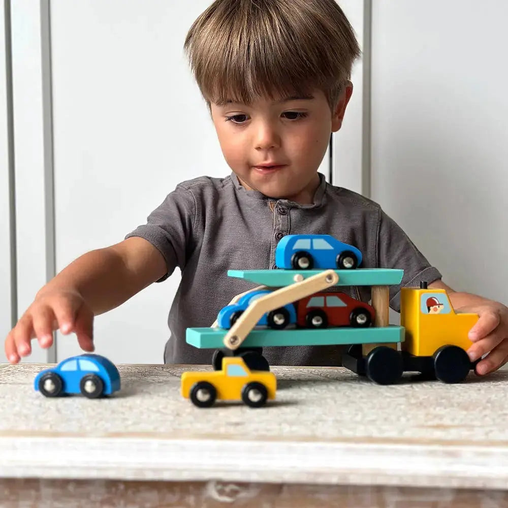 Kind spielt mit dem Holztransporter und den verschiedenen kleinen Fahrzeugen.