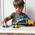 Kind spielt mit dem Holztransporter und den verschiedenen kleinen Fahrzeugen.