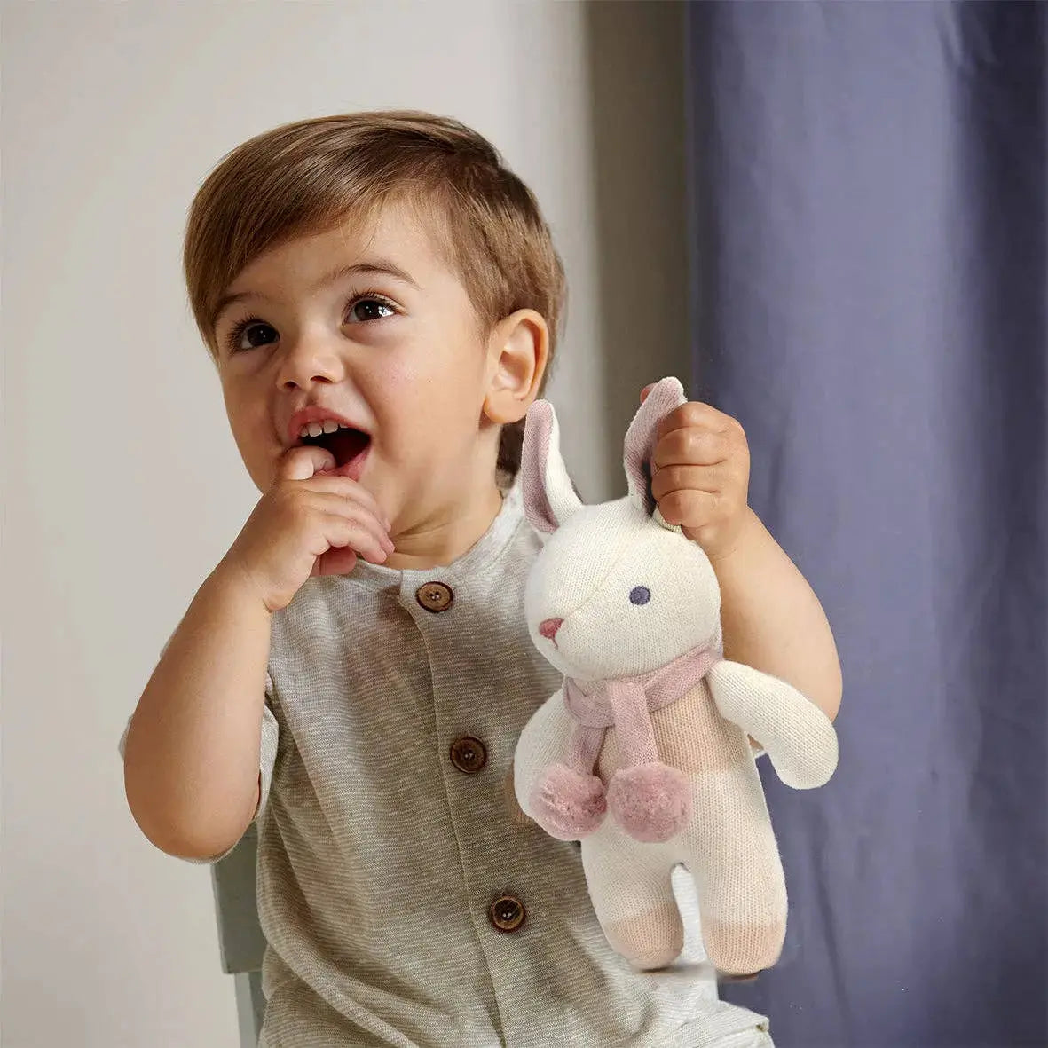 Baby hält das weiche Häschen mit Rassel in den Händen und entdeckt das Spielzeug.