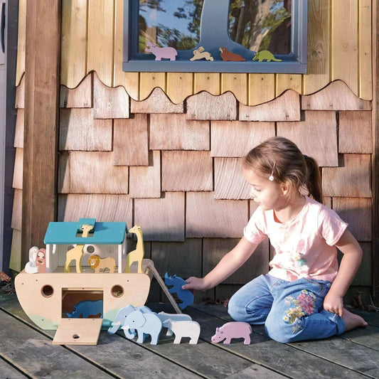 Kind spielt mit der Arche Noah aus Holz und verschiedenen Tierfiguren