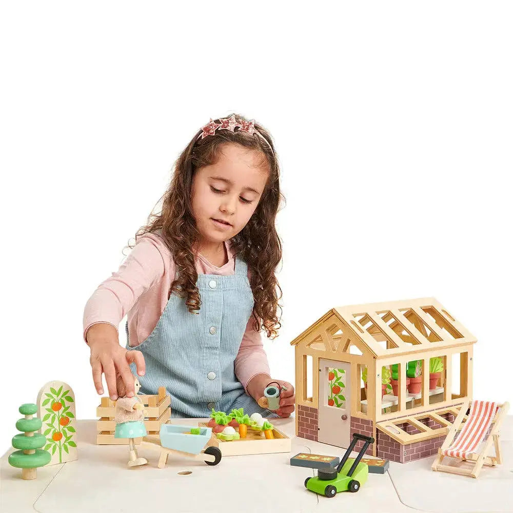 Kind spielt mit dem Holz Gewächshaus und gestaltet seinen eigenen kleinen Garten