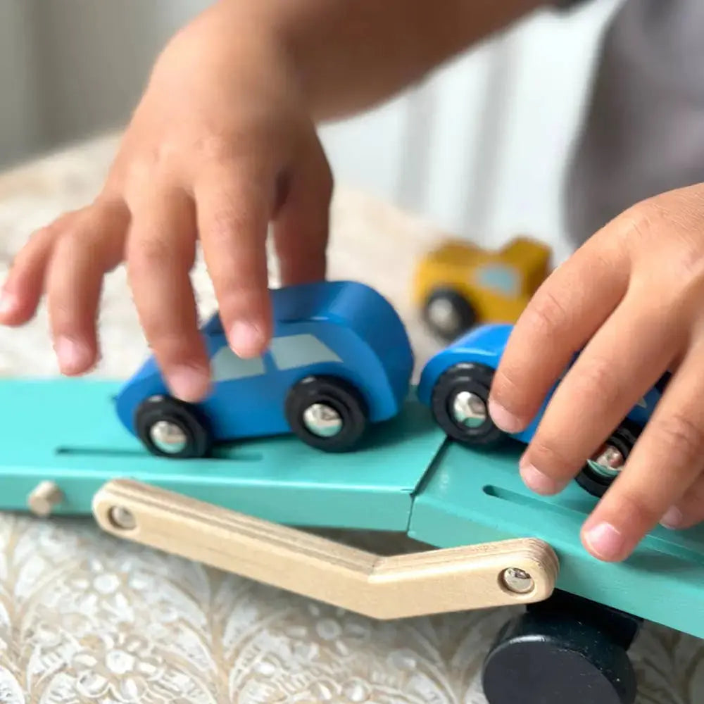 Kind spielt mit dem Autotransporter, der beweglichen Ladefläche und den kleinen Holzautos.