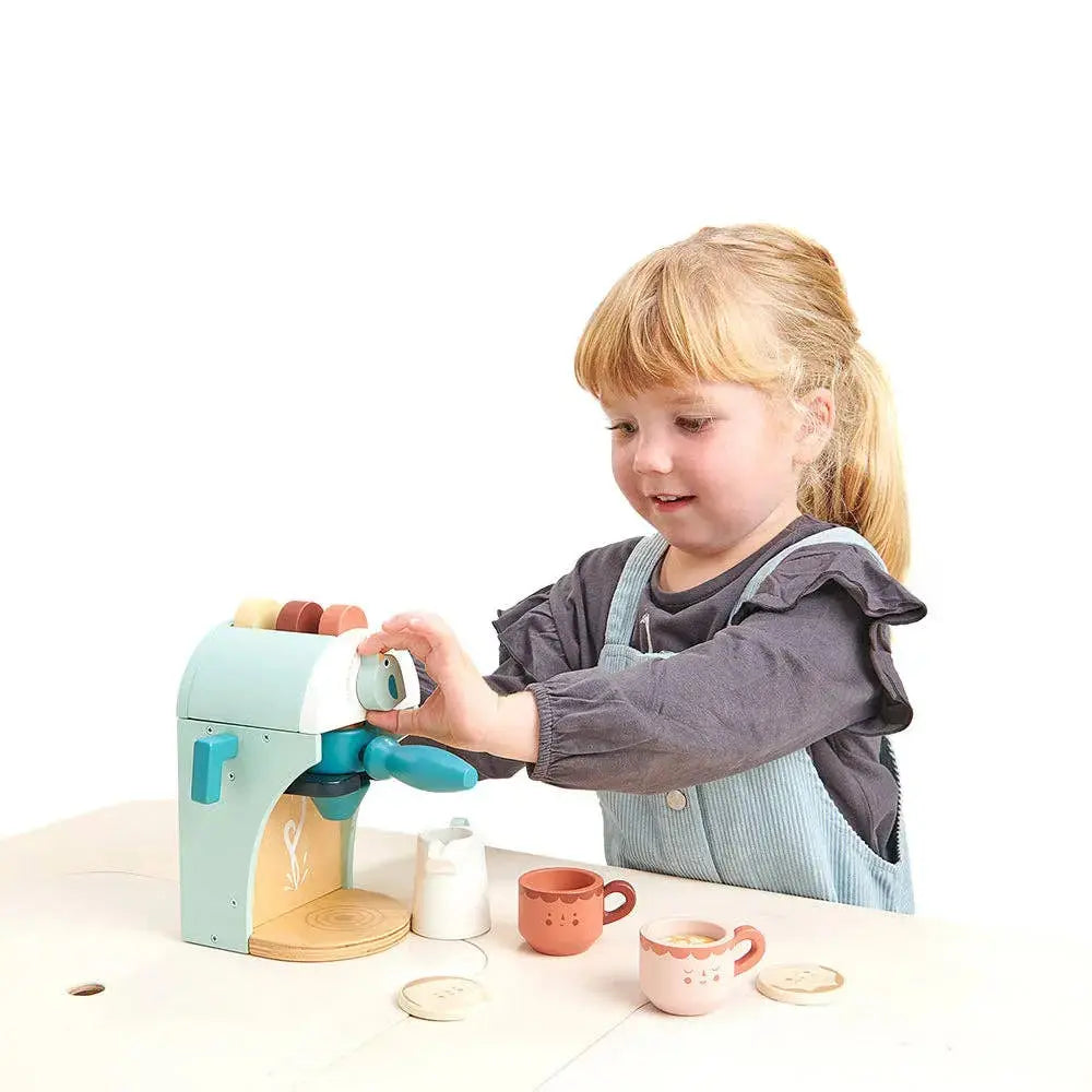 Kind spielt mit der Babyccino Kaffeemaschine und bereitet fantasievoll einen Kaffee zu.