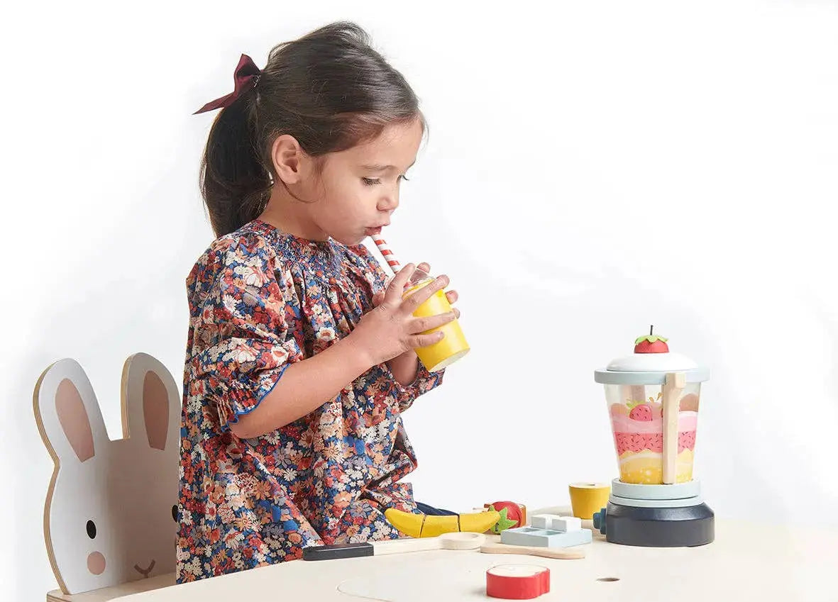 Kind spielt mit dem Fruchtmixer aus Holz und bereitet fantasievoll einen Smoothie zu.